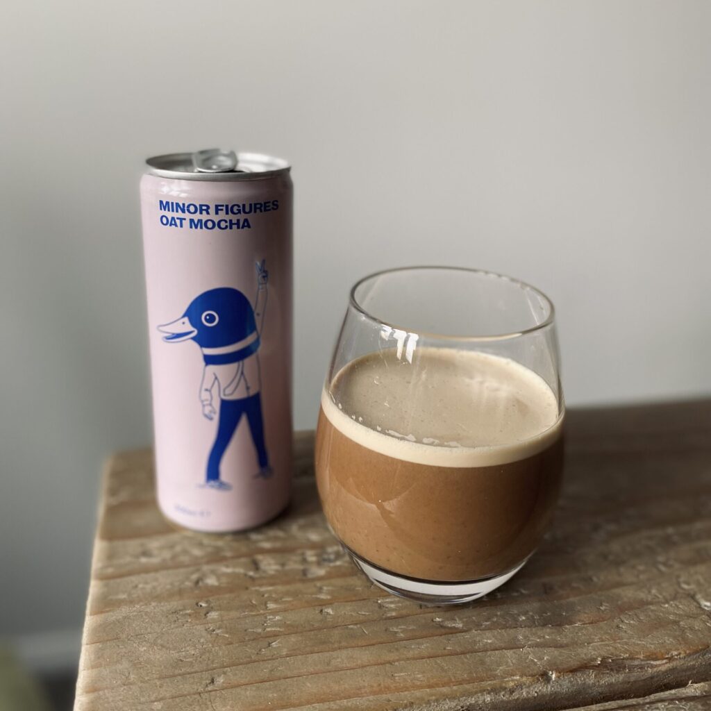A poured out glass of Minor Figures cold brew coffee next to the can