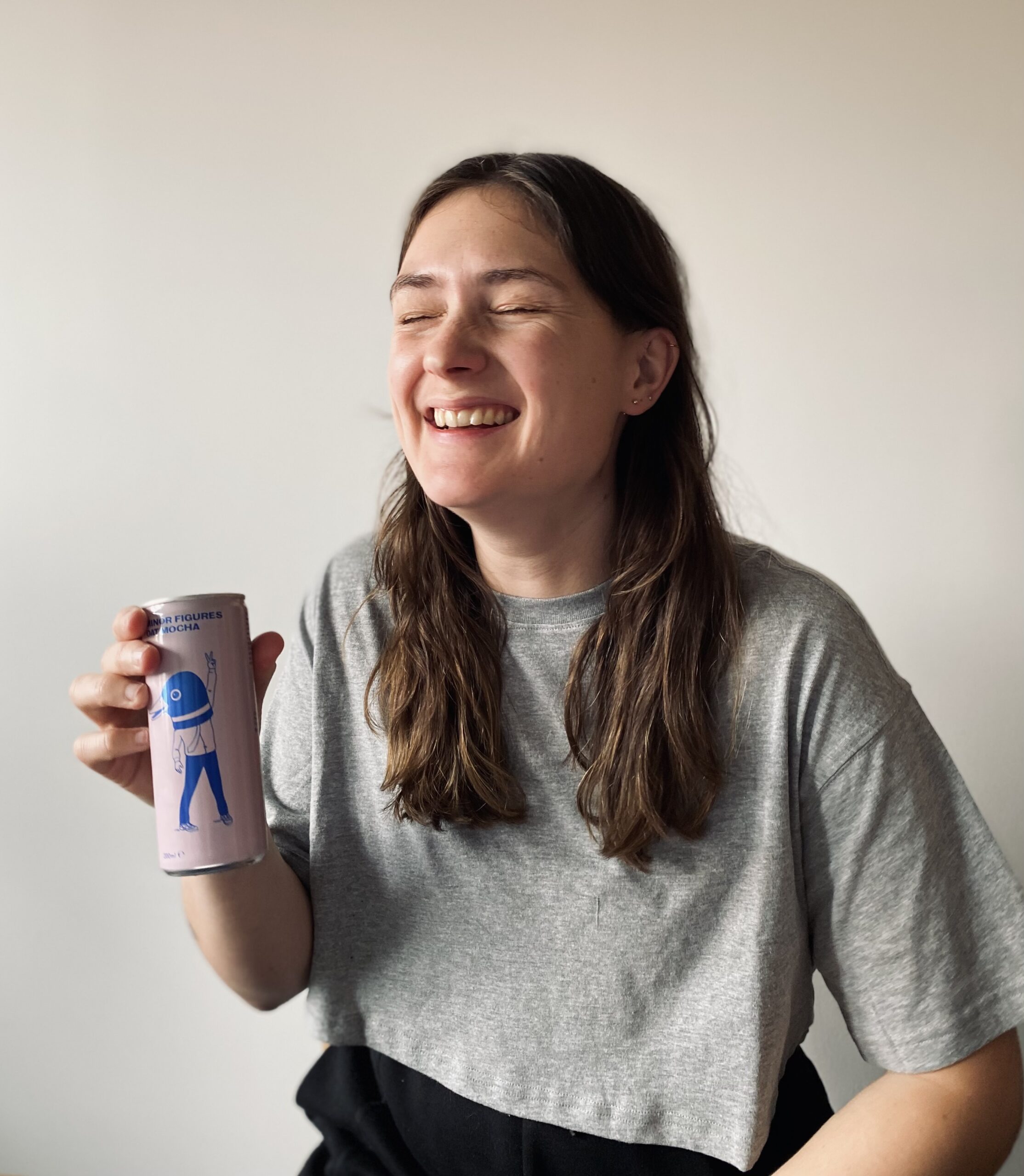 Lucy laughing at the can of Minor Figures cold brew coffee