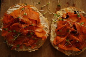 Two bagel slices with vegan creamy cheese and smoked carrot lox on top