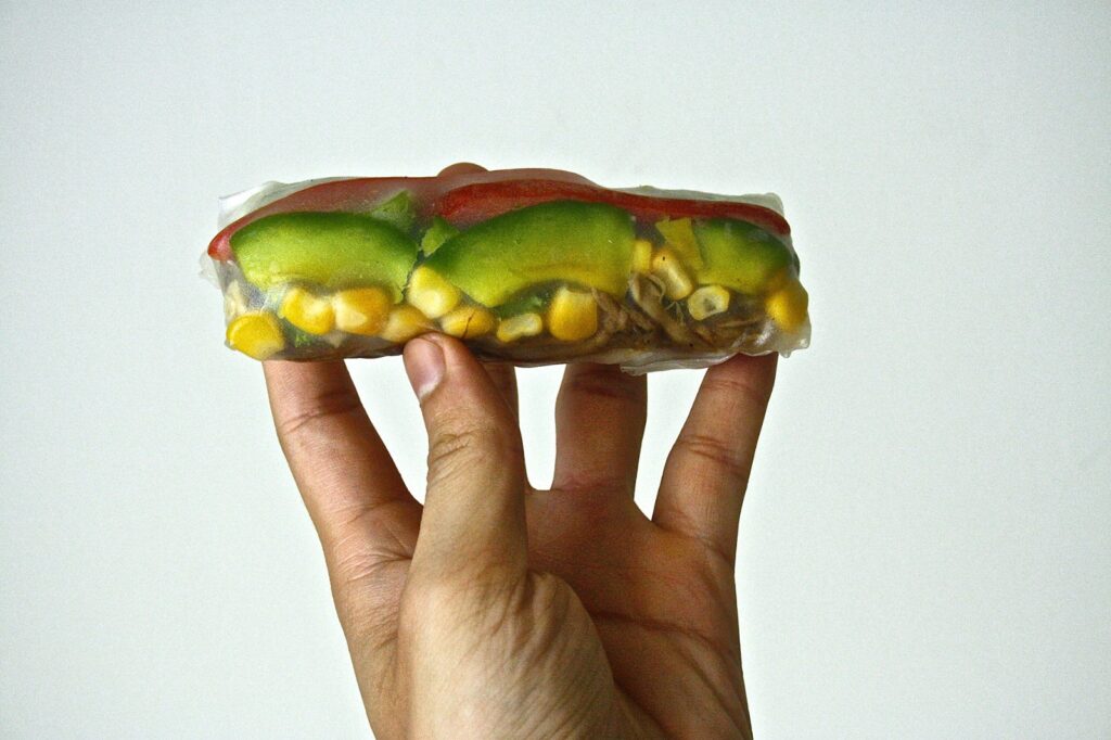 A fusion vegan Vietnamese spring roll being held up into the air