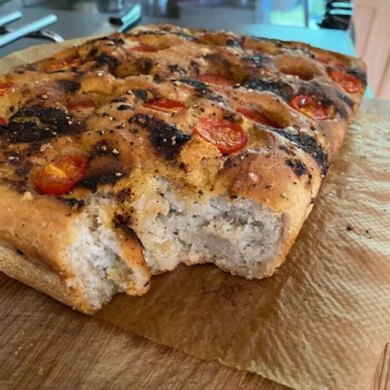 A gluten-free focaccia with a chunk taken out of it