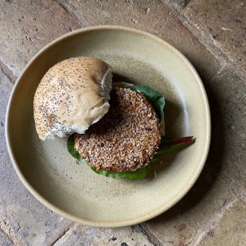 vegan jackfruit burger patty inside a bun on a brown plate