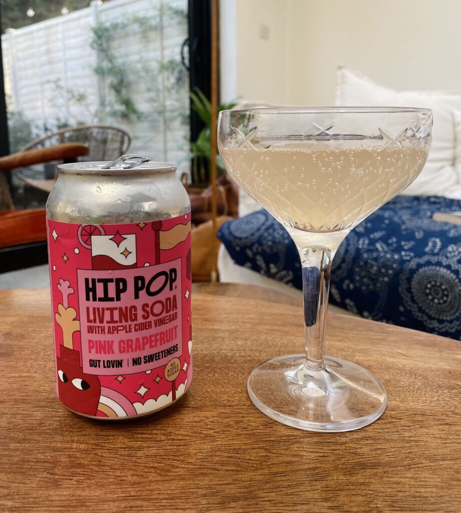A glass of Hip Pop's grapefruit living soda on a wooden table