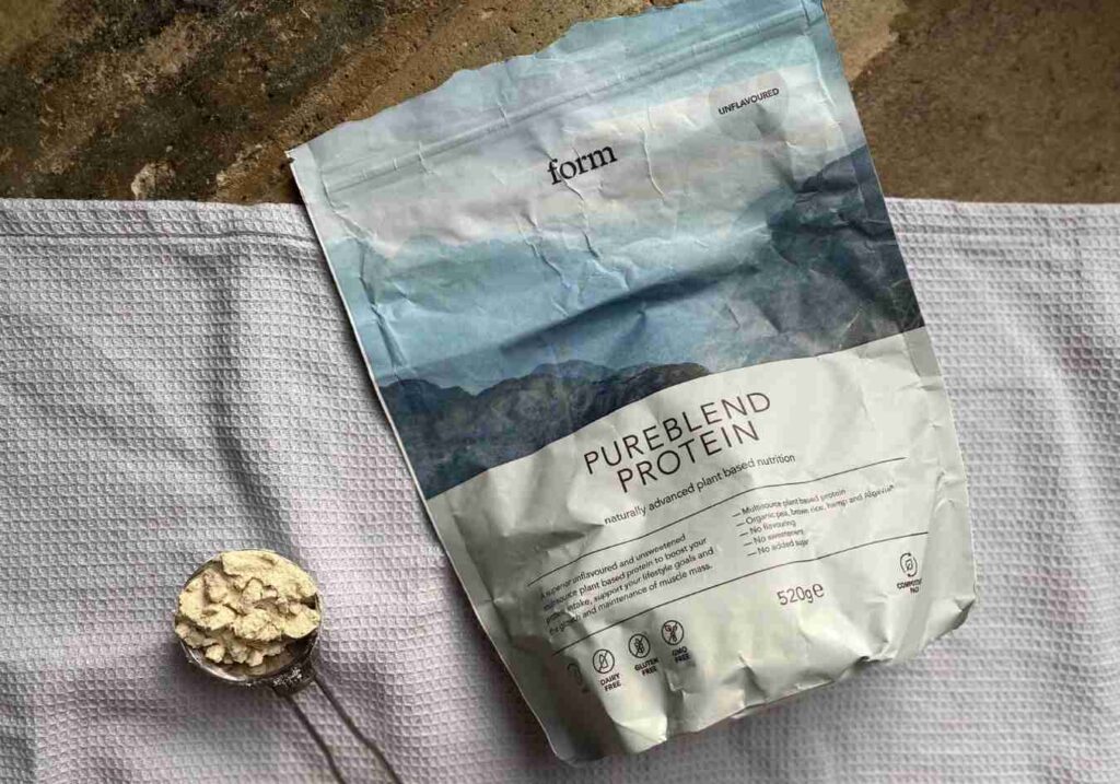 A spoonful of vegan protein powder next to the bag of form nutrition - one of the best vegan protein powders in the UK
