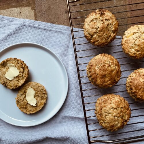 vegan cheese scones on a cooling rack with a cut scone covered in butter