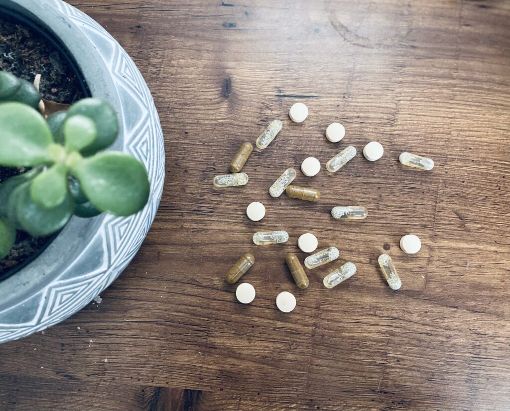 A pile of the best vegan multivitamins on a wooden table next to a plant