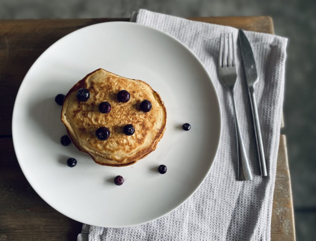 An aerial view of a stack of vegan buttermilk pancakes with blueberries scattered on top