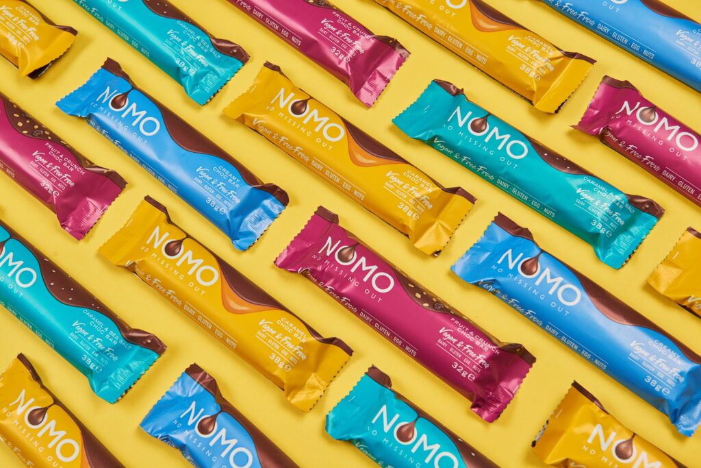 rows of vegan chocolate bars by NOMO on a yellow background