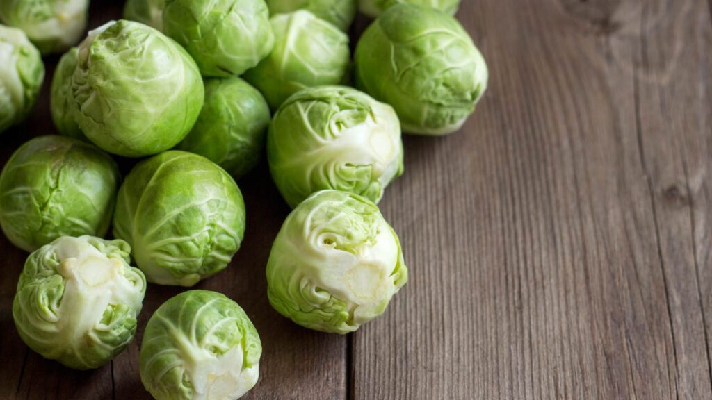 A pile of brussels sprouts on a wooden worktop which are a great vegan source of omega 3