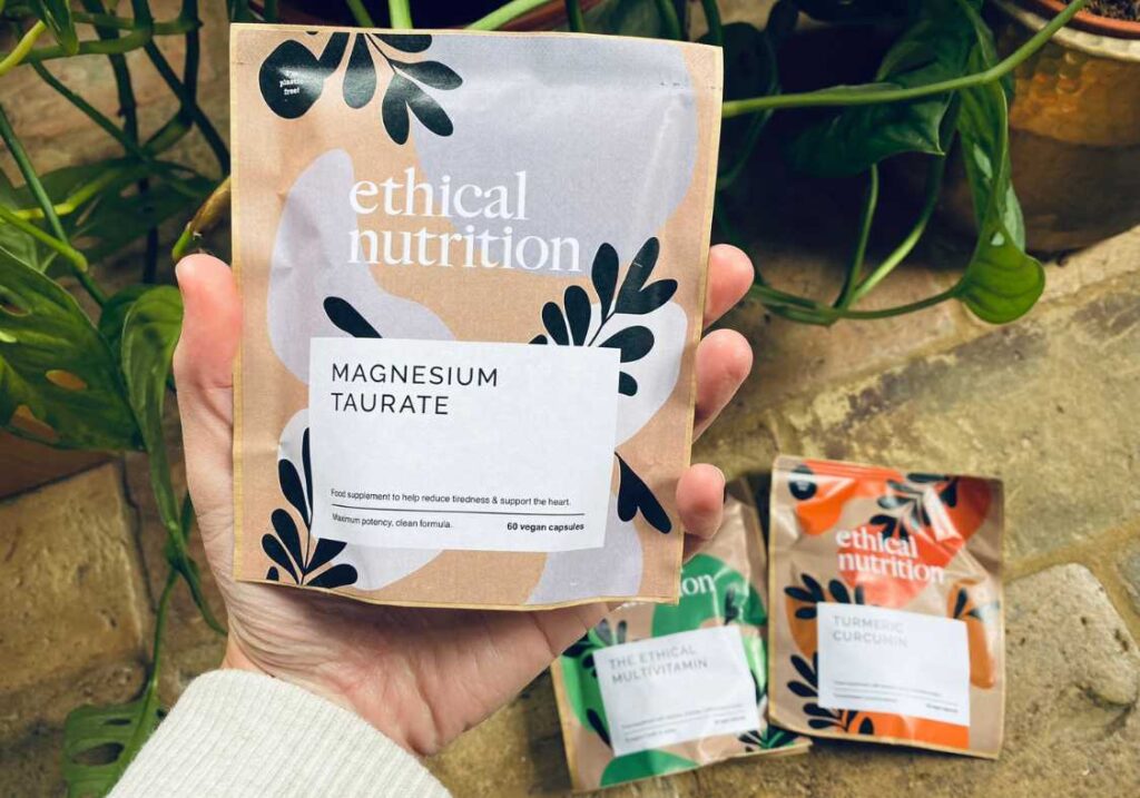A bag of Magnesium supplements held up to the camera with two other vegan supplements in the background by Ethical Nutrition