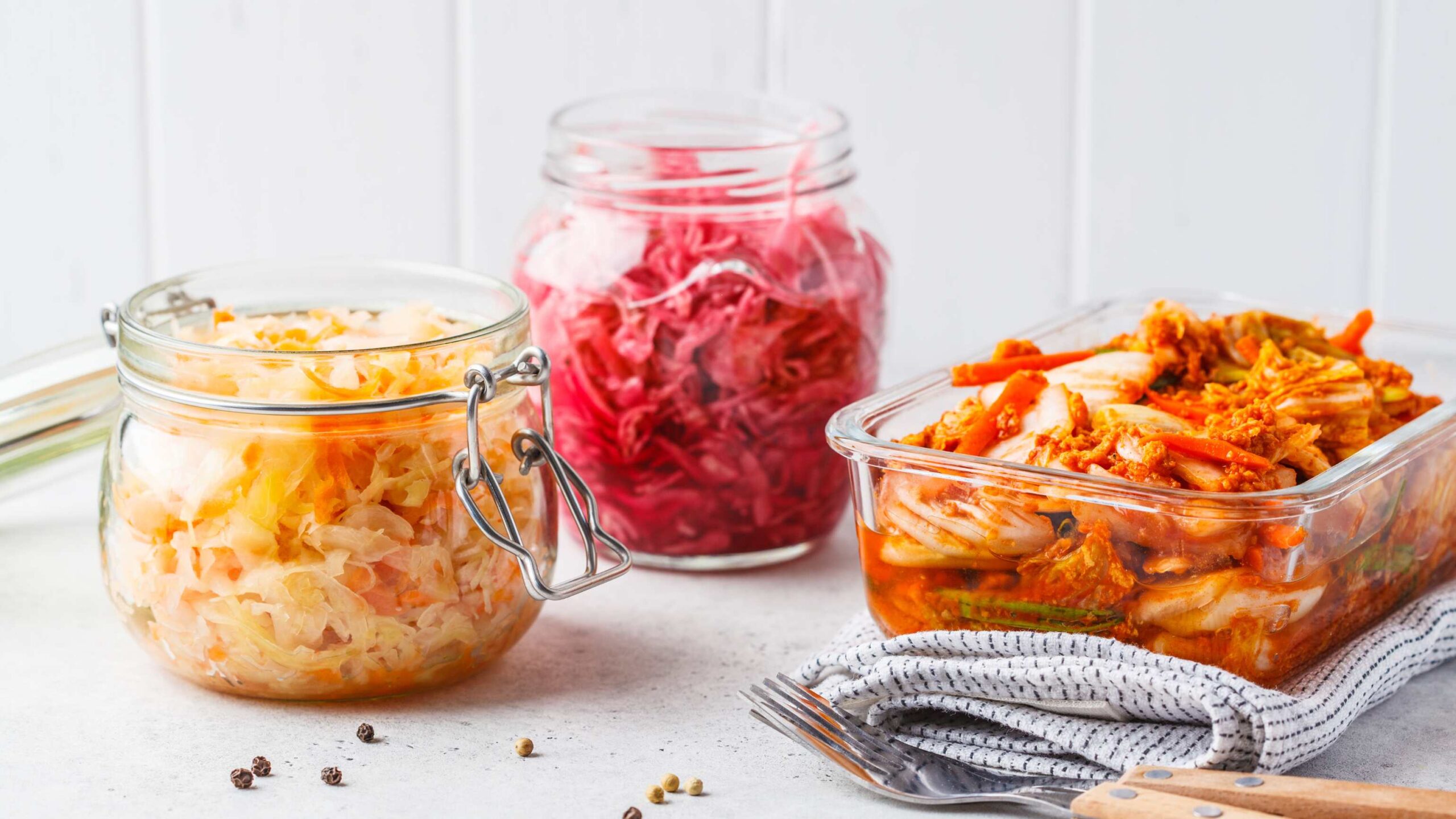 An array of vegan probiotic foods in jars that you should be eating like kimchi and sauerkraut