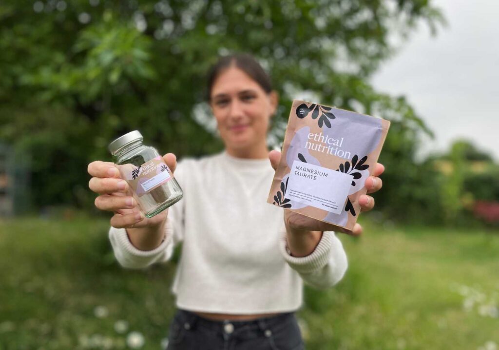Lucy holding up a bag of magnesium supplements and a glass jar in the garden as part of her Ethical Nutrition review