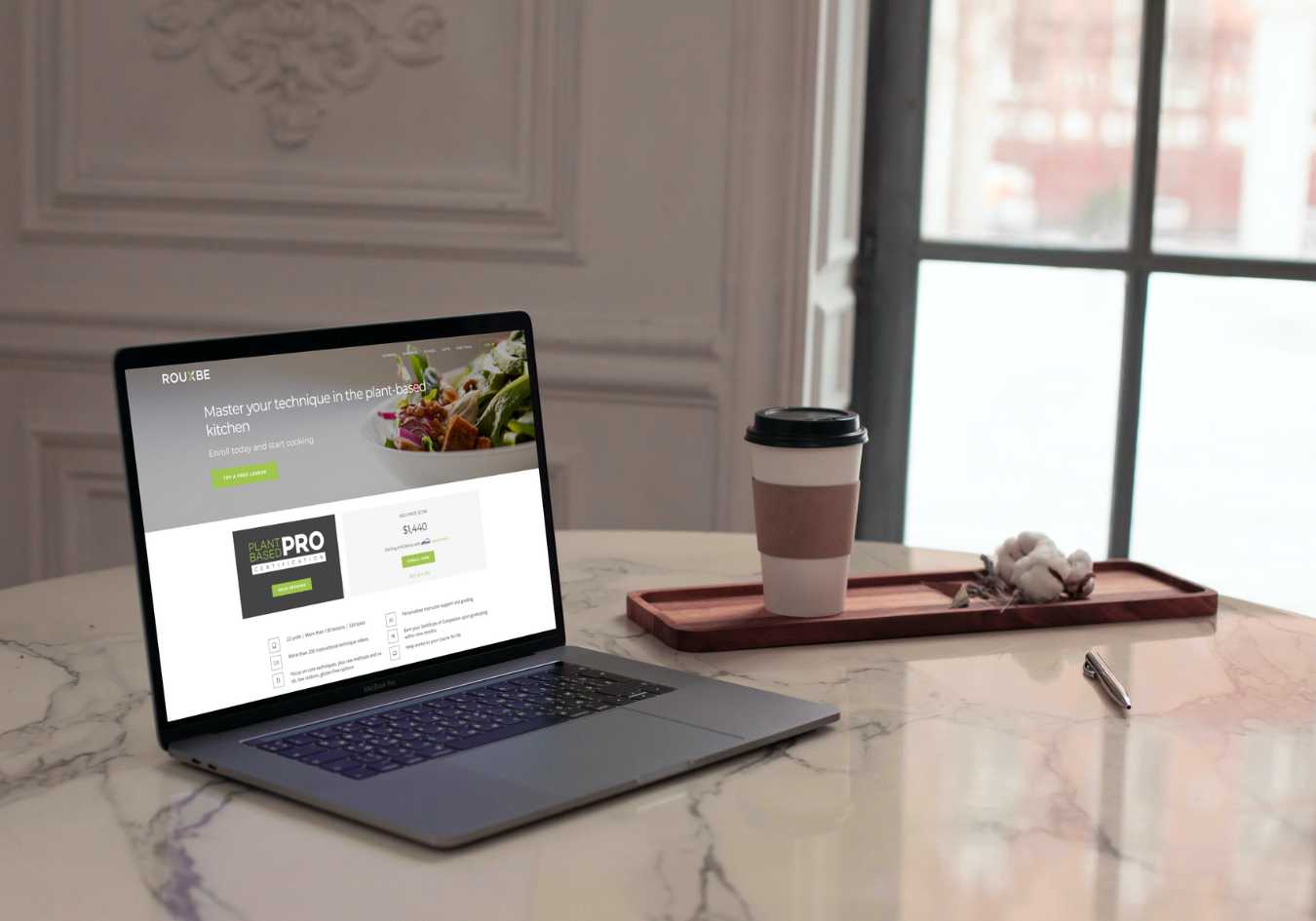 Rouxbe plant based pro course website open on a laptop in a kitchen with a cup of coffee nearby