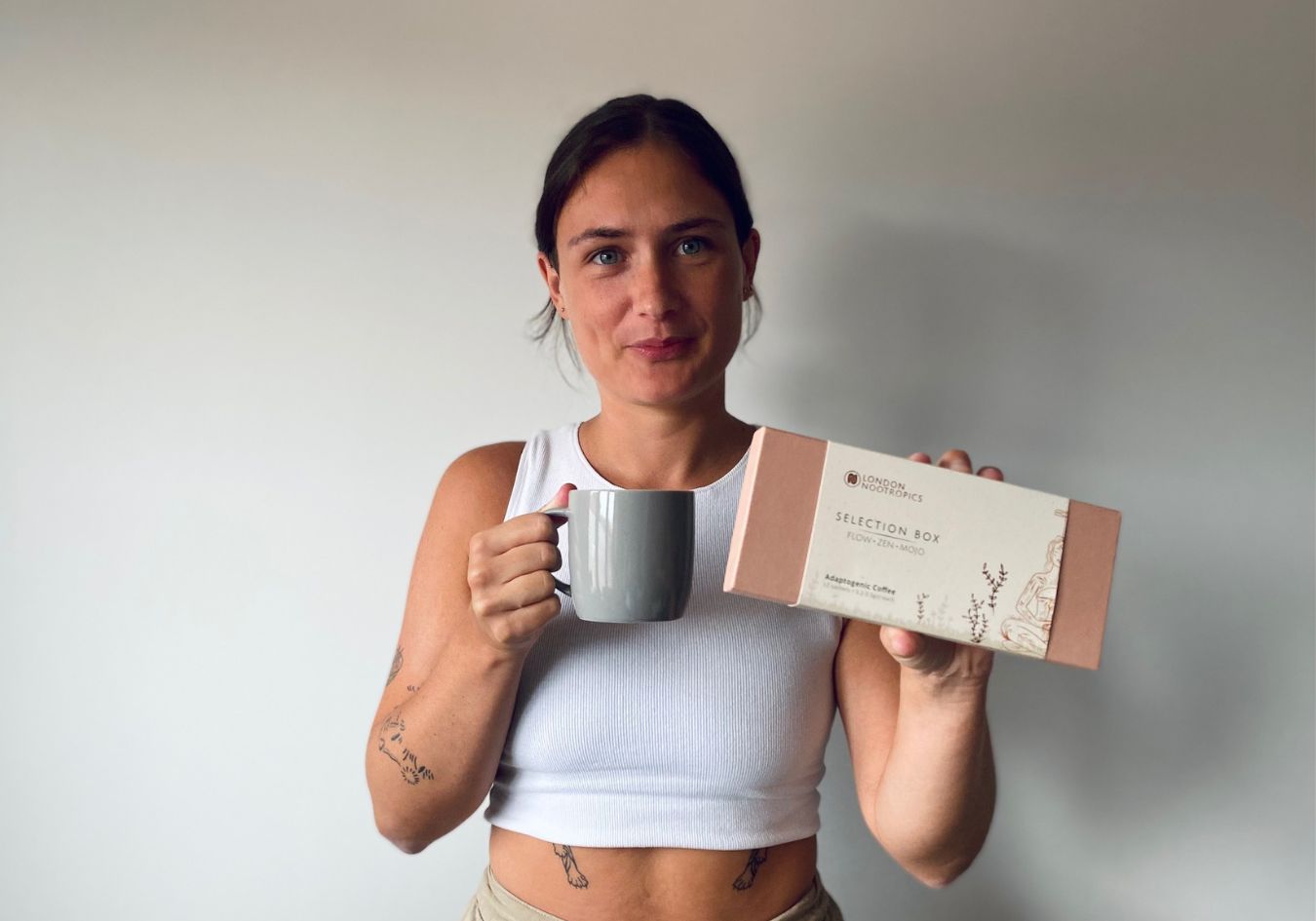 Lucy holding up a selection box with a cup of nootropic coffee in her other hand as tried for this London Nootropic review