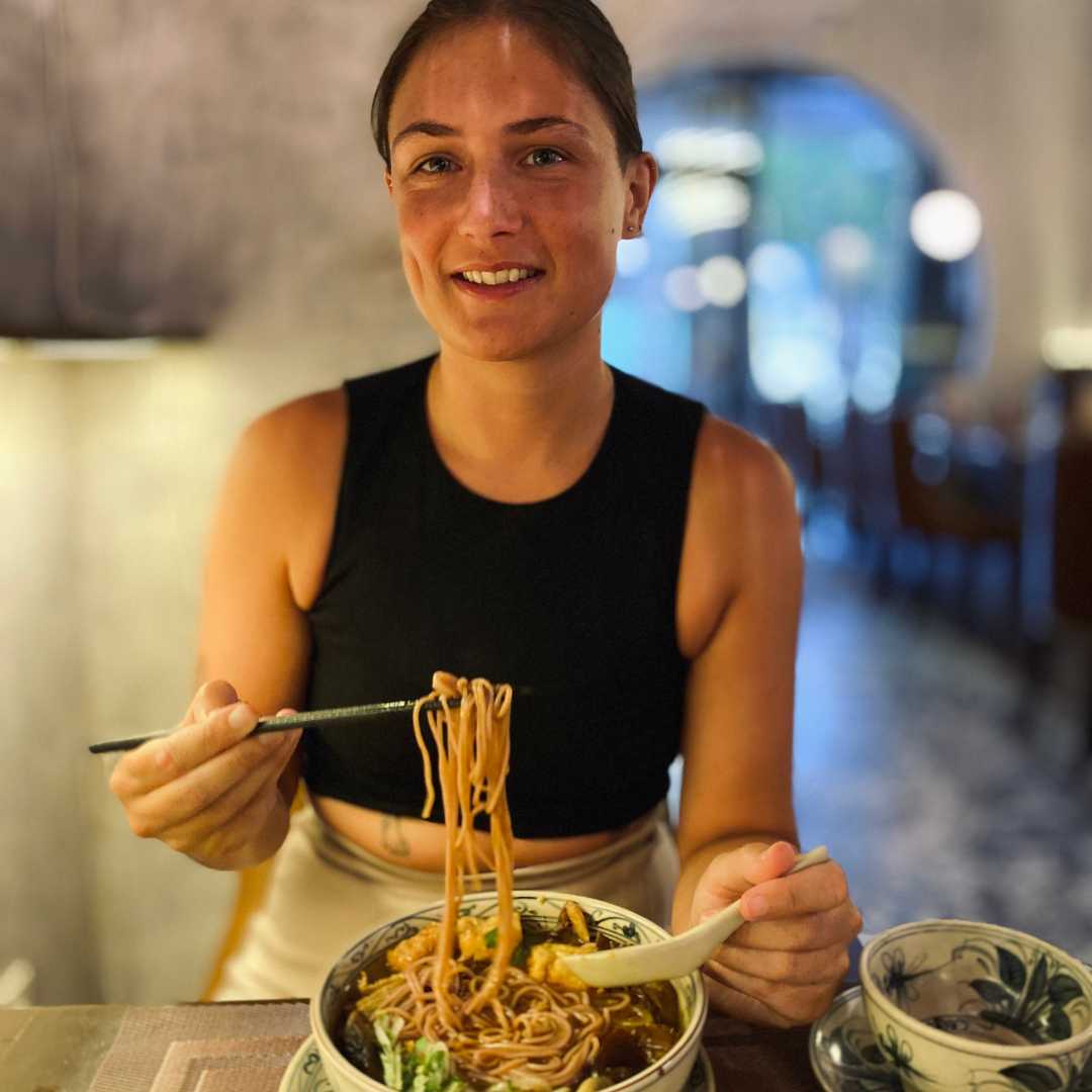 Lucy the founder of Edible Ethics vegan food blog eating vegan noodles in a plant based restaurant