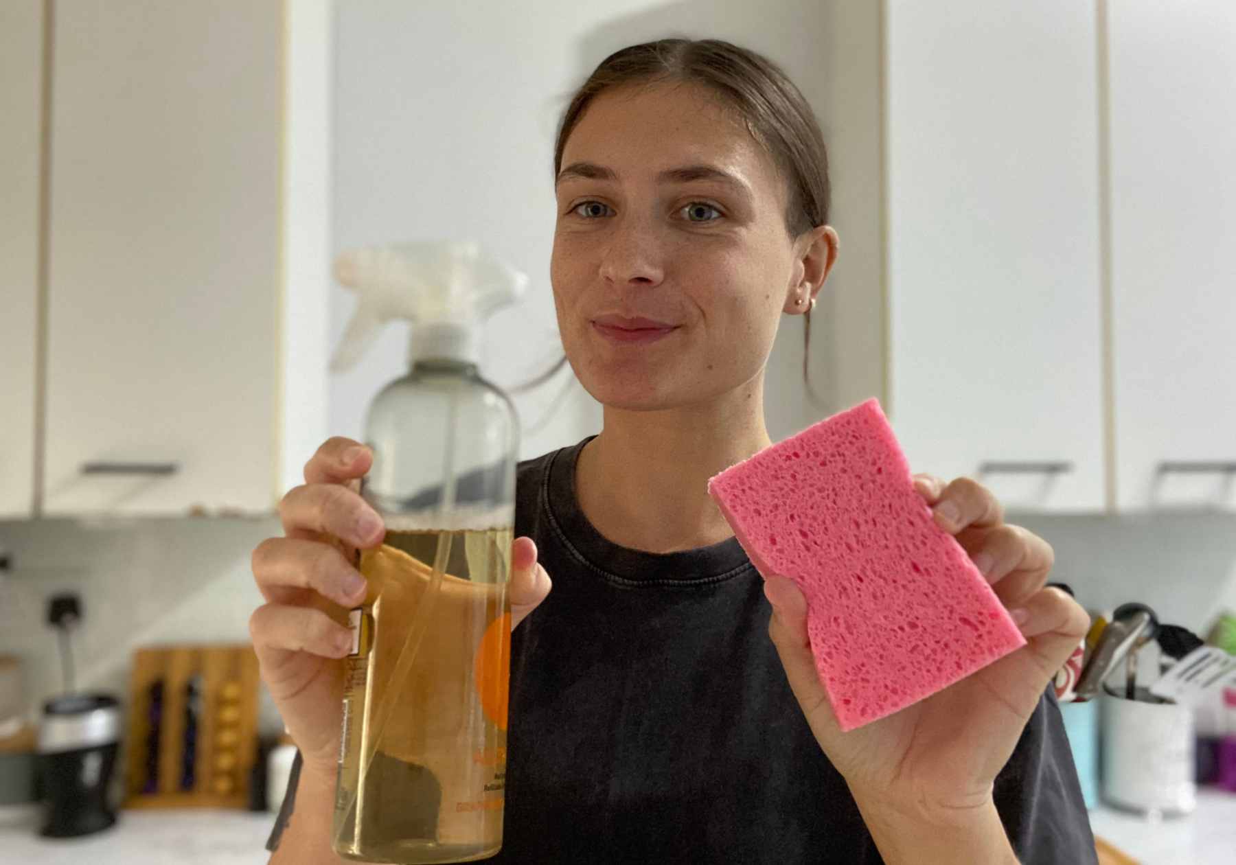 Lucy holding some vegan cleaning products up towards the camera