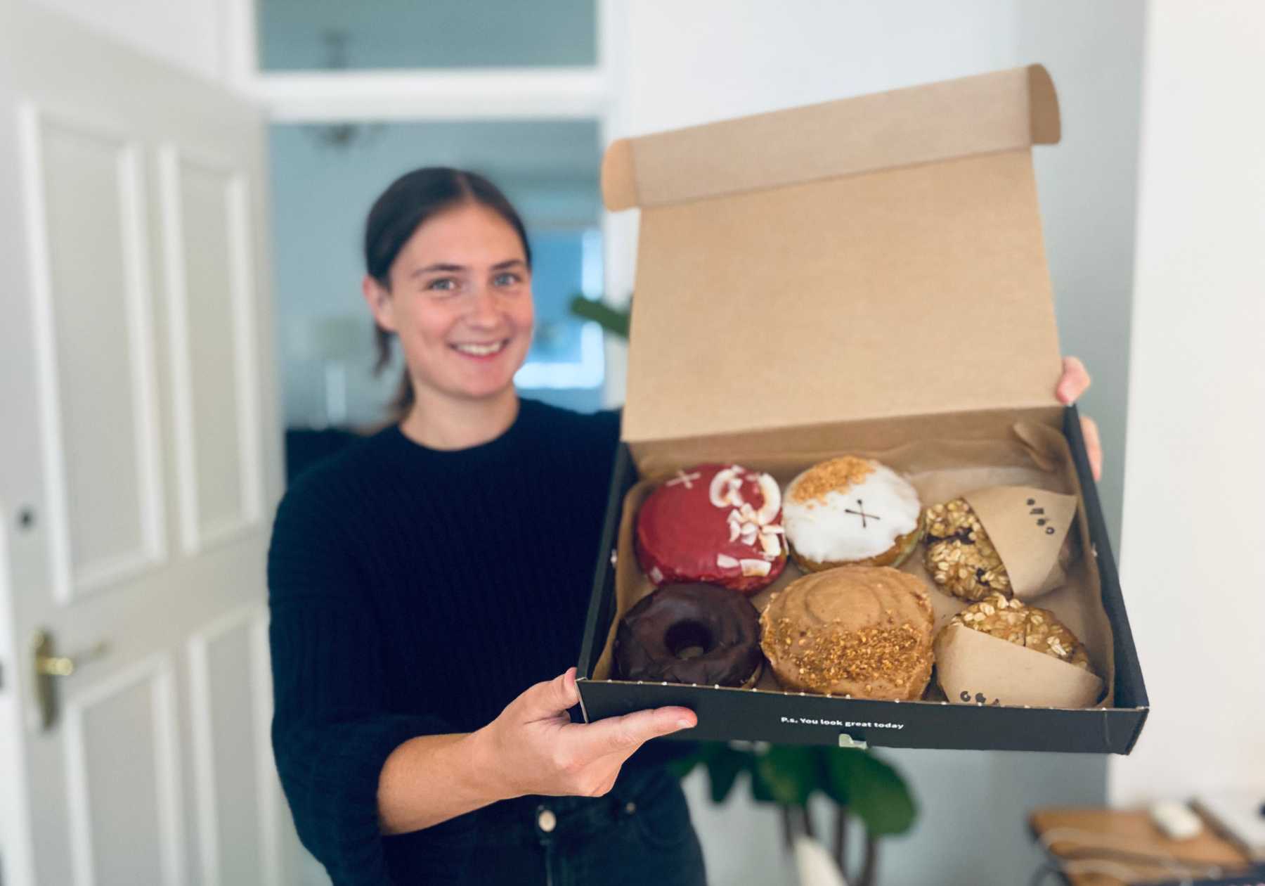 Lucy holding a box of cookies and doughnuts from the best vegan cake delivery service in the UK