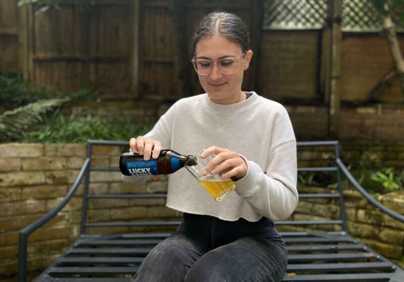 Lucy pouring a Lucky Saint alcohol-free beer into a glass for this Lucky Saint review