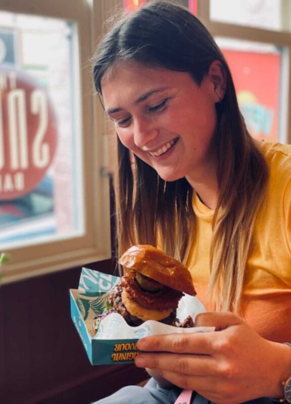 Lucy holding a vegan burger in her hands