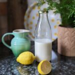 A bottle of vegan buttermilk next to a jug of vegan milk and lemons for acid
