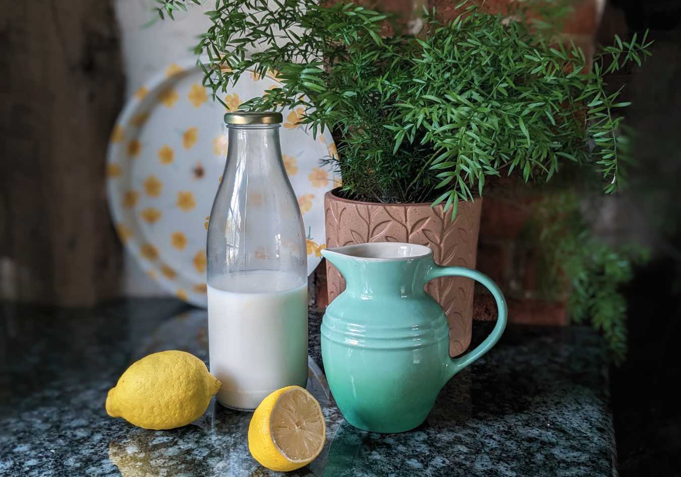 A jug of vegan buttermilk next to some lemon and vegan milk