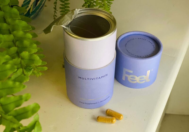 An opened tub of Feel Multivitamin with two capsules next to it that I tested for this Feel Multivitamin review