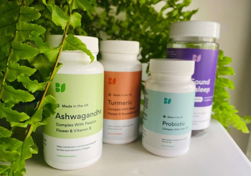 A close up of BetterVits supplements on a white surface infront of a green plant for this BetterVits review